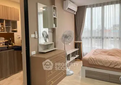 Modern bedroom with stylish decor and adjacent kitchen area in cozy apartment.