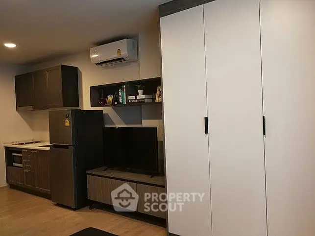 Modern apartment interior with sleek kitchen and living area featuring built-in cabinets and air conditioning.