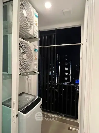 Modern laundry area with washing machine and city view from balcony at night.