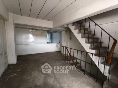 Spacious industrial-style interior with concrete floors and staircase, ideal for creative renovation.