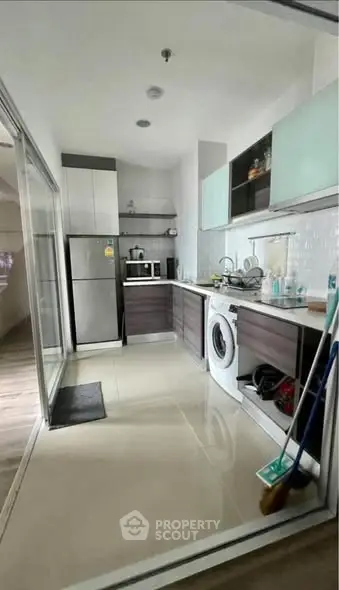 Modern kitchen with sleek cabinets and built-in appliances, featuring a washing machine and microwave.