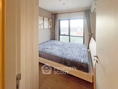 Cozy bedroom with large window offering city views, featuring a comfortable bed and stylish decor.