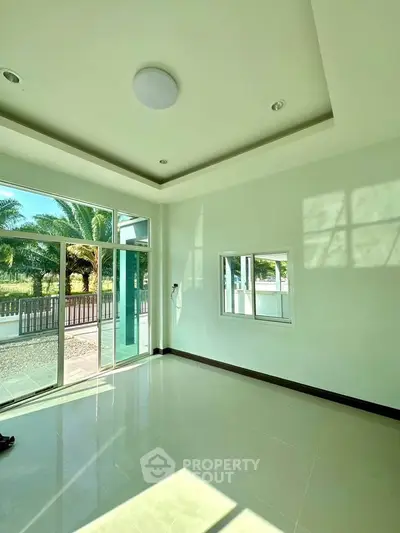 Bright empty room with large windows and garden view, perfect for customization.