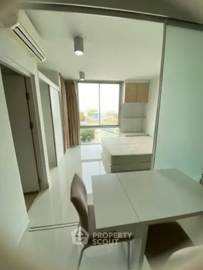 Modern studio apartment with large window and sleek furnishings, perfect for urban living.