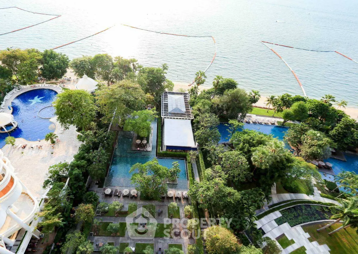 Stunning aerial view of luxurious beachfront property with pools and lush gardens.