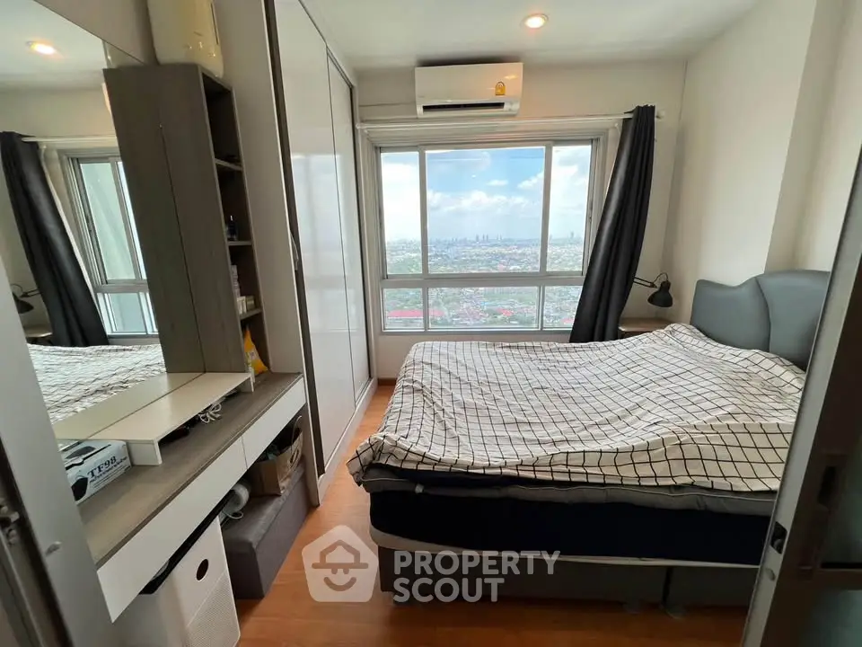 Cozy bedroom with city view, featuring modern furnishings and ample natural light.