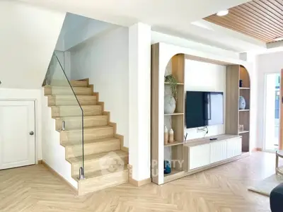 Modern living room with stylish wooden staircase and built-in TV unit, featuring elegant decor and natural light.