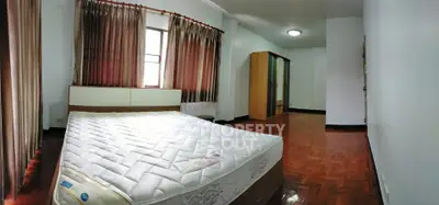 Spacious bedroom with large windows and wooden flooring, perfect for comfort and relaxation.