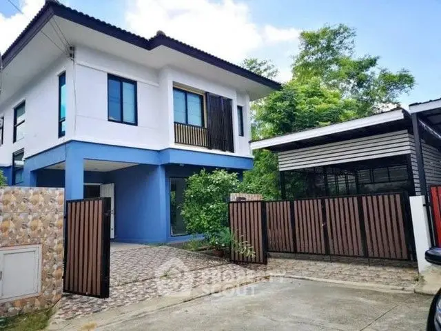 Modern two-story house with gated driveway and lush greenery.
