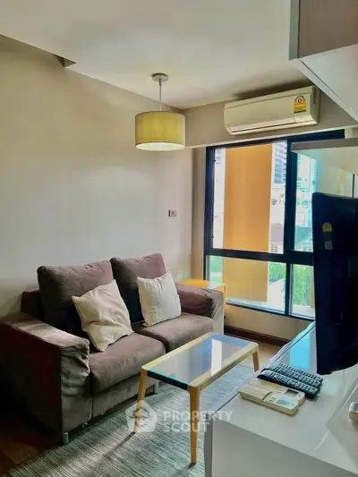 Cozy living room with modern sofa and large window offering city views.