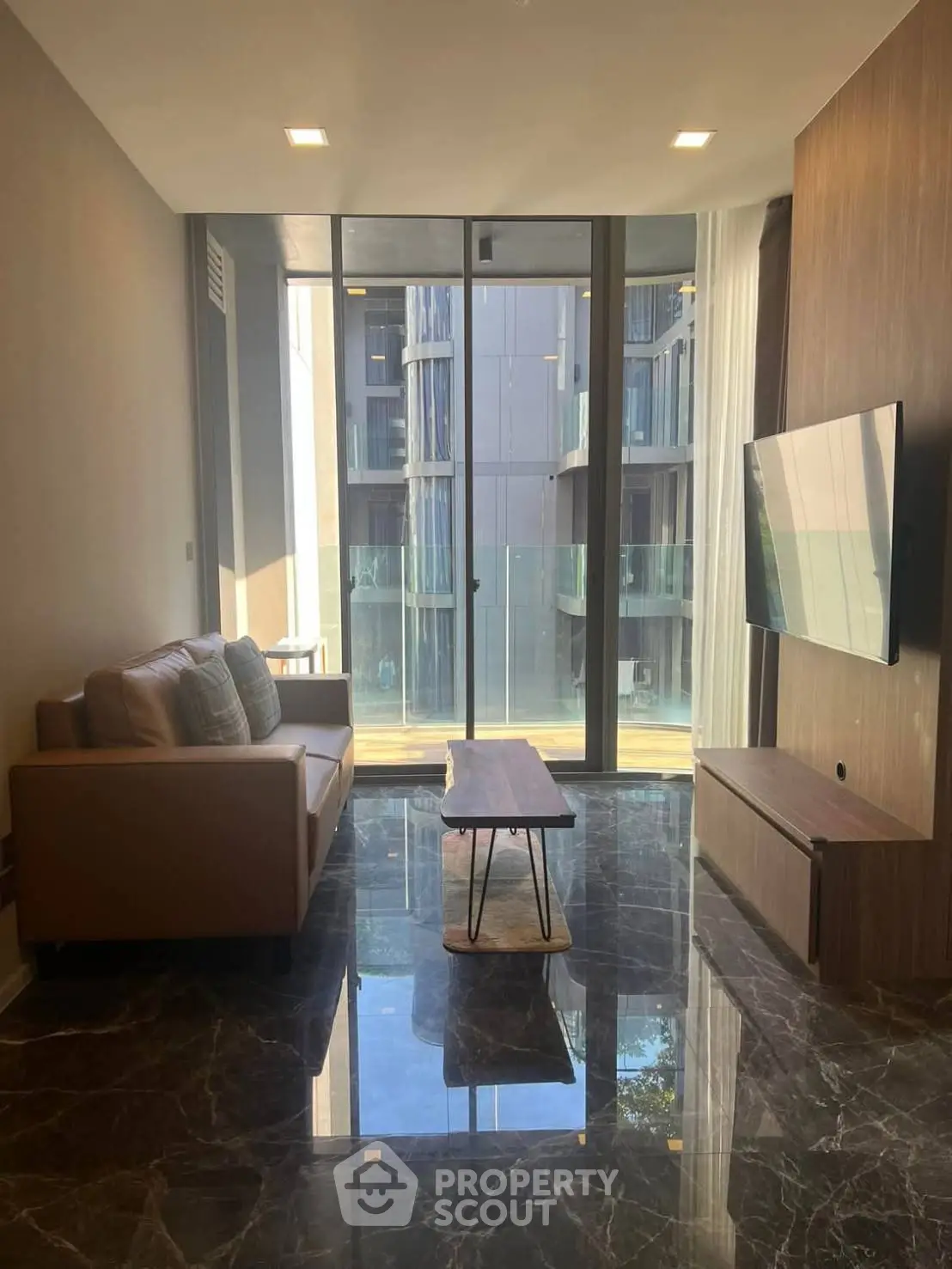 Modern living room with sleek design and floor-to-ceiling windows in urban apartment.