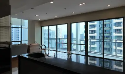 Spacious modern apartment with large windows offering stunning city views, featuring an open kitchen layout.