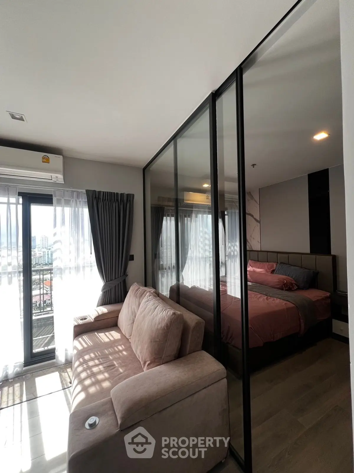Modern apartment with glass partition, cozy living area, and stylish bedroom.
