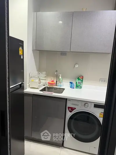 Modern compact kitchen with washing machine and sleek cabinetry in a stylish apartment.