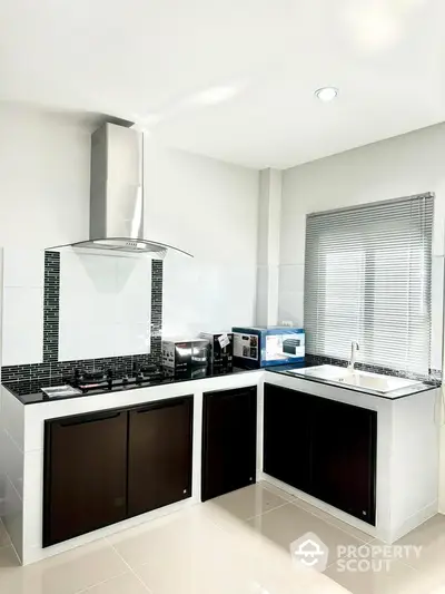 Modern kitchen with sleek design, featuring gas stove and ample natural light.