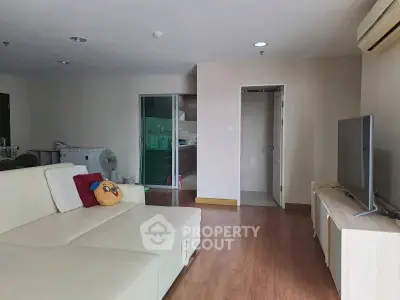 Spacious living room with modern decor and natural light, featuring a comfortable sofa and flat-screen TV.