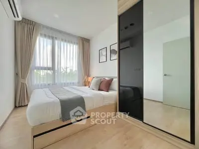 Modern bedroom with large window, stylish decor, and mirrored wardrobe in a bright apartment.