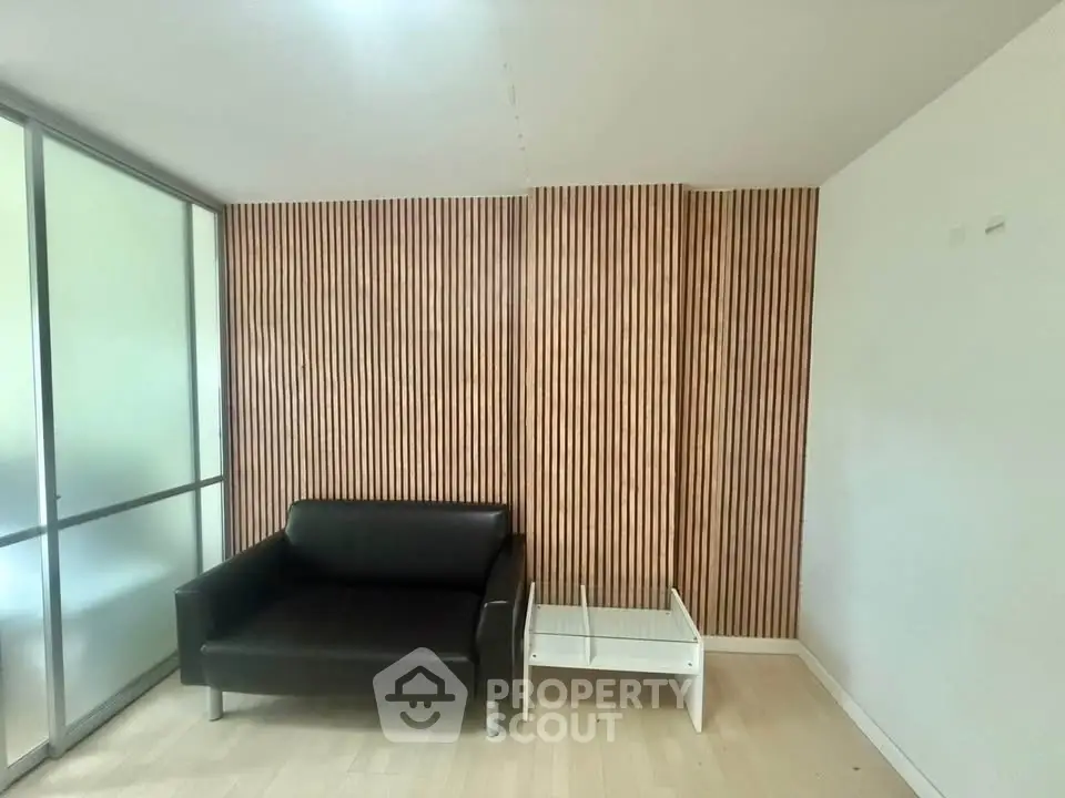 Modern living room with sleek black sofa and wooden accent wall