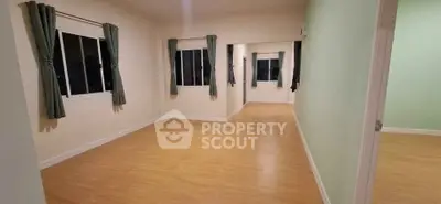 Spacious empty room with wooden flooring and large windows, perfect for customization.