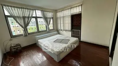 Spacious bedroom with large windows and wooden flooring, offering ample natural light and a cozy atmosphere.