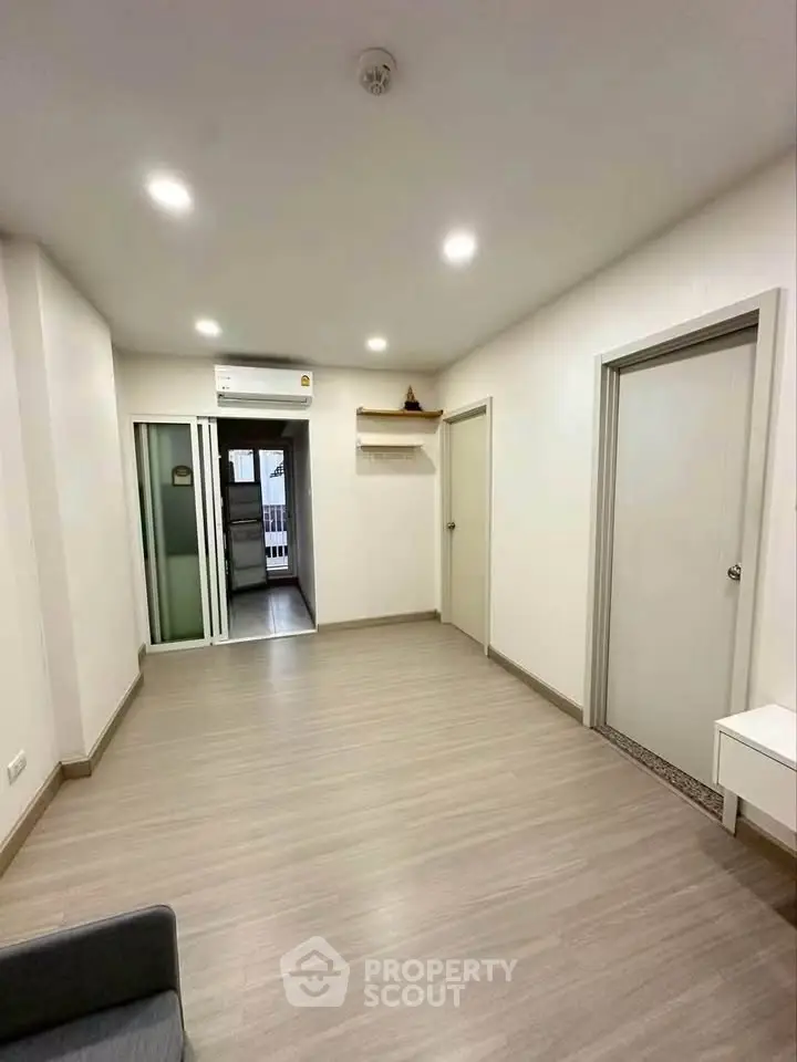 Spacious modern living room with sleek flooring and bright lighting, perfect for comfortable living.