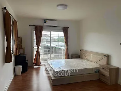 Spacious bedroom with natural light, featuring a large window and modern furnishings.