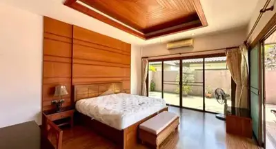 Spacious bedroom with wooden accents and large windows opening to a patio.