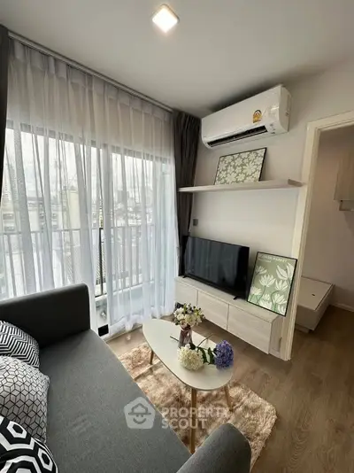 Modern living room with stylish decor and natural light, featuring a cozy sofa and wall-mounted TV.