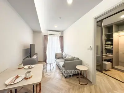 Modern living room with cozy sofa and dining area, featuring elegant wood flooring and natural light.