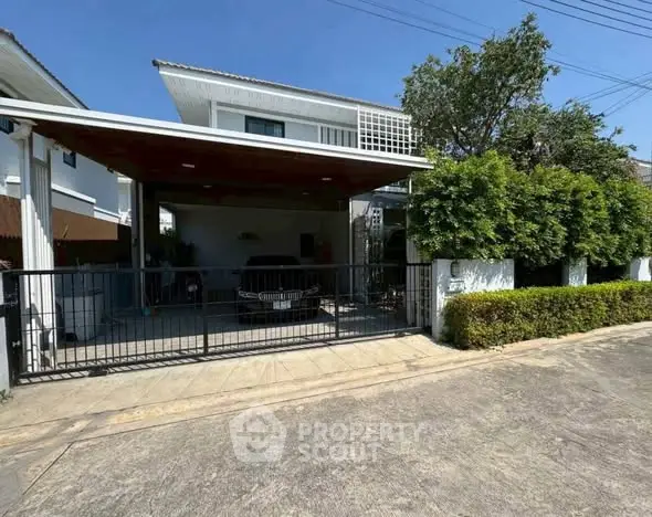 Charming two-story house with carport and lush greenery in a serene neighborhood.