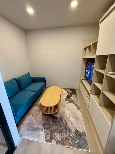 Cozy living room with modern blue sofa, stylish rug, and built-in shelving unit.