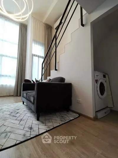 Modern living room with stylish staircase and washing machine in cozy apartment.