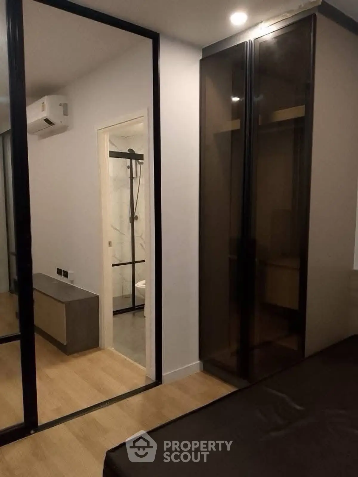 Modern bedroom with glass wardrobe and view into sleek bathroom