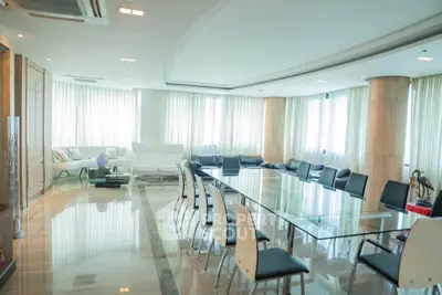 Spacious modern living room with elegant glass dining table and panoramic windows.