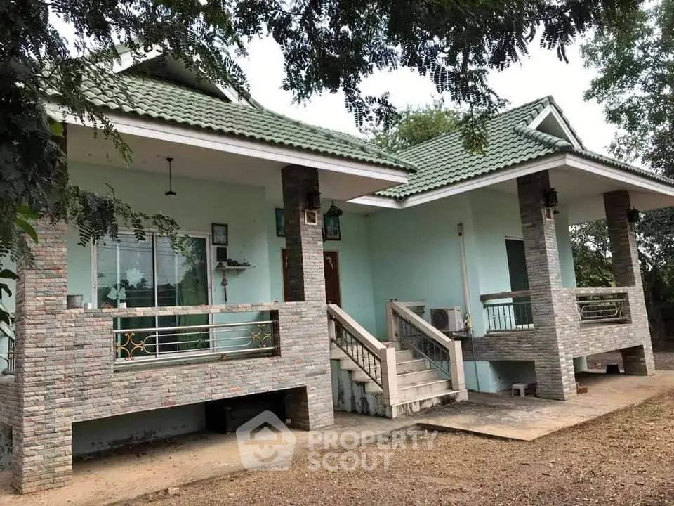 Charming single-story home with green roof and spacious front porch in a serene setting.