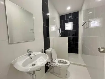 Modern bathroom with sleek black and white tiles, featuring a shower and contemporary fixtures.