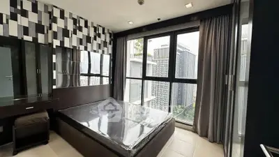 Modern bedroom with large windows offering stunning city views in a high-rise apartment.