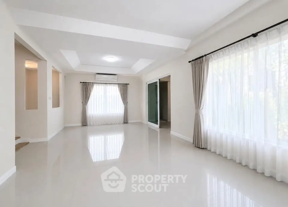 Spacious empty living room with large windows and elegant curtains