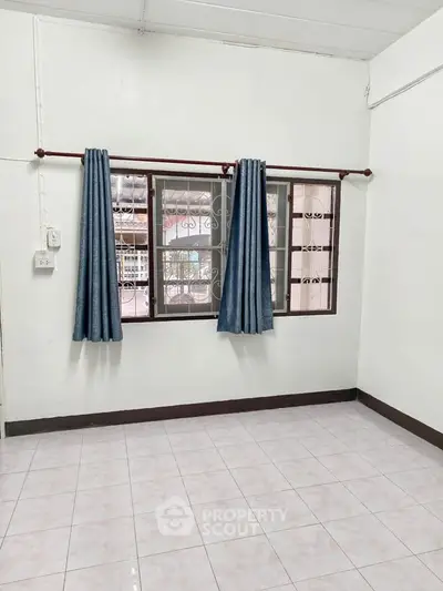 Spacious empty room with tiled floor and large window, perfect for customization.