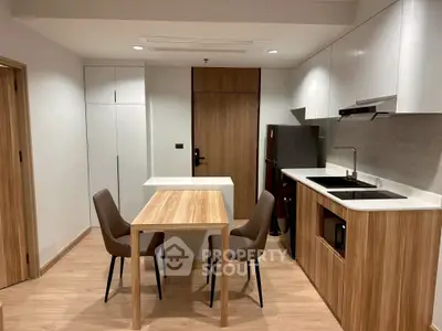 Modern kitchen with sleek wooden dining table and chairs, featuring built-in appliances and minimalist design.