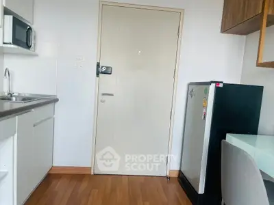 Compact kitchen with modern appliances and wooden flooring in a cozy apartment.