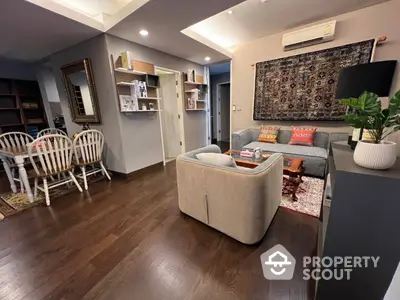 Cozy and inviting living room with warm wooden floors, comfortable seating, and a well-organized bookshelf, perfect for relaxation and entertainment.