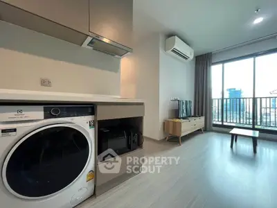 Modern living room with city view, featuring sleek kitchen appliances and stylish decor.