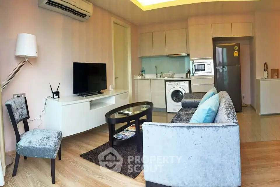 Modern living room with open kitchen, featuring sleek furniture and appliances, ideal for urban living.