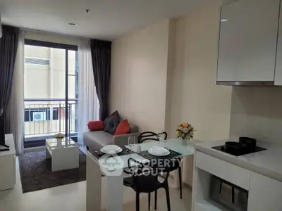 Modern living room with open kitchen, stylish decor, and balcony access in a cozy apartment.