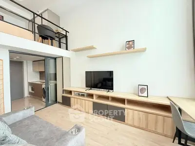 Modern living room with loft, sleek furniture, and open kitchen layout.