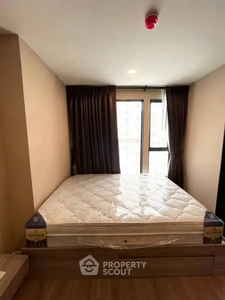 Cozy bedroom with large window and natural light, featuring a comfortable bed and elegant curtains.