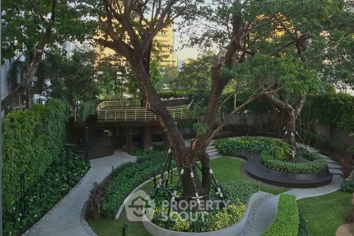Lush garden with mature trees and landscaped pathways in a serene residential complex.