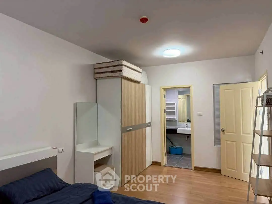 Spacious bedroom with modern design and ensuite bathroom, featuring wooden flooring and ample storage space.