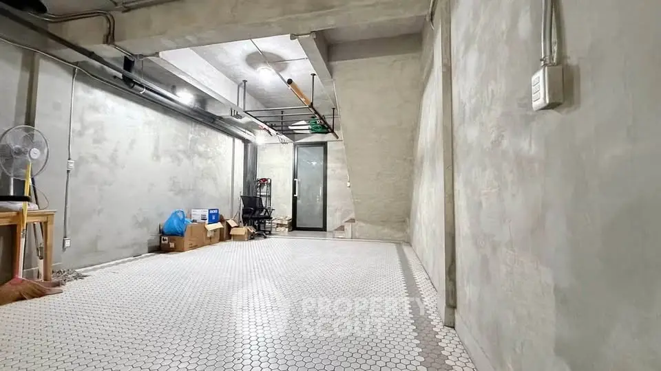 Spacious industrial-style storage room with concrete walls and hexagonal tile flooring.